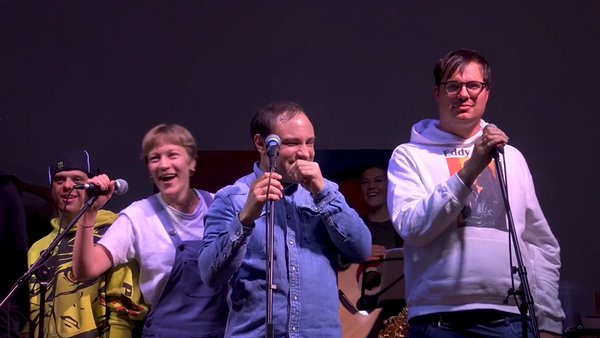 3 Personen am Mikrofon bei einem Auftritt