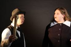 Zwei Personen, eine hält einen großen Knochen, beide in formeller Kleidung.