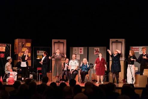 Menschen stehen nebeneinander auf der Bühne und schauen in unterschiedliche Richtungen.